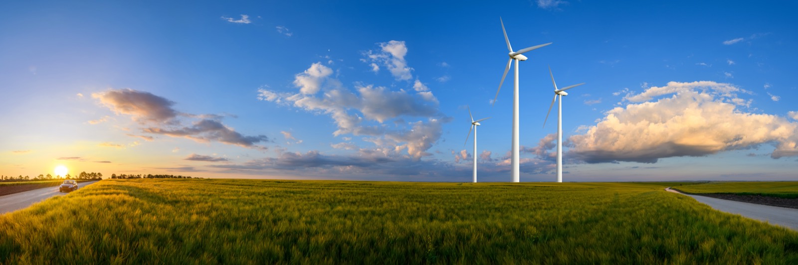 Wind turbines over fields at sunset
